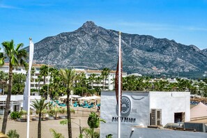 A beachside hotel with a mountain backdrop, palm trees, and a sign reading "BAND'S BEACH".