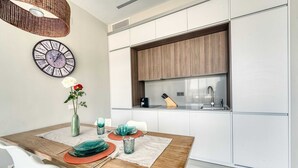 Una cocina moderna con armarios blancos, encimera de madera y horno empotrado.