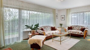 A living room with two floral sofas, a coffee table, a small table with a plant, and a fur throw on a wooden ottoman. - Apartment '1' with Mountain View, Private Terrace and Wi-Fi (Sankt Peter)