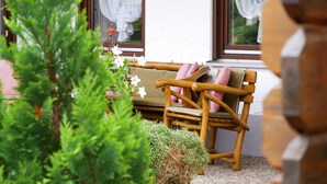 A wooden bench with cushions, a potted plant, and a window with curtains. - Apartment '1' with Mountain View, Private Terrace and Wi-Fi (Sankt Peter)