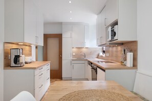 A modern kitchen with white cabinets, a wooden countertop, a built-in oven, and a microwave. - Apartment '1' with Mountain View, Private Terrace and Wi-Fi (Sankt Peter)
