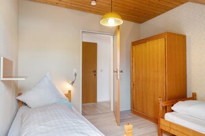 Ein Schlafzimmer mit einem Bett, einem Kleiderschrank und einer Tür zu einem anderen Raum.