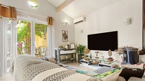 A modern living room with a sofa, a TV, a glass coffee table, and a fireplace. - Villa 'Palmiers En Couleurs' with Mountain View, Private Pool, and Wi-Fi (Cuers)