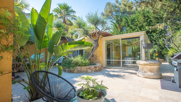 A modern outdoor patio with a glass door, a black chair, and a potted plant. - Villa 'Palmiers En Couleurs' with Mountain View, Private Pool, and Wi-Fi (Cuers)