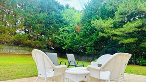Eine Terrasse mit Korbmöbeln, darunter Stühle und ein Tisch, auf einer Betonfläche.