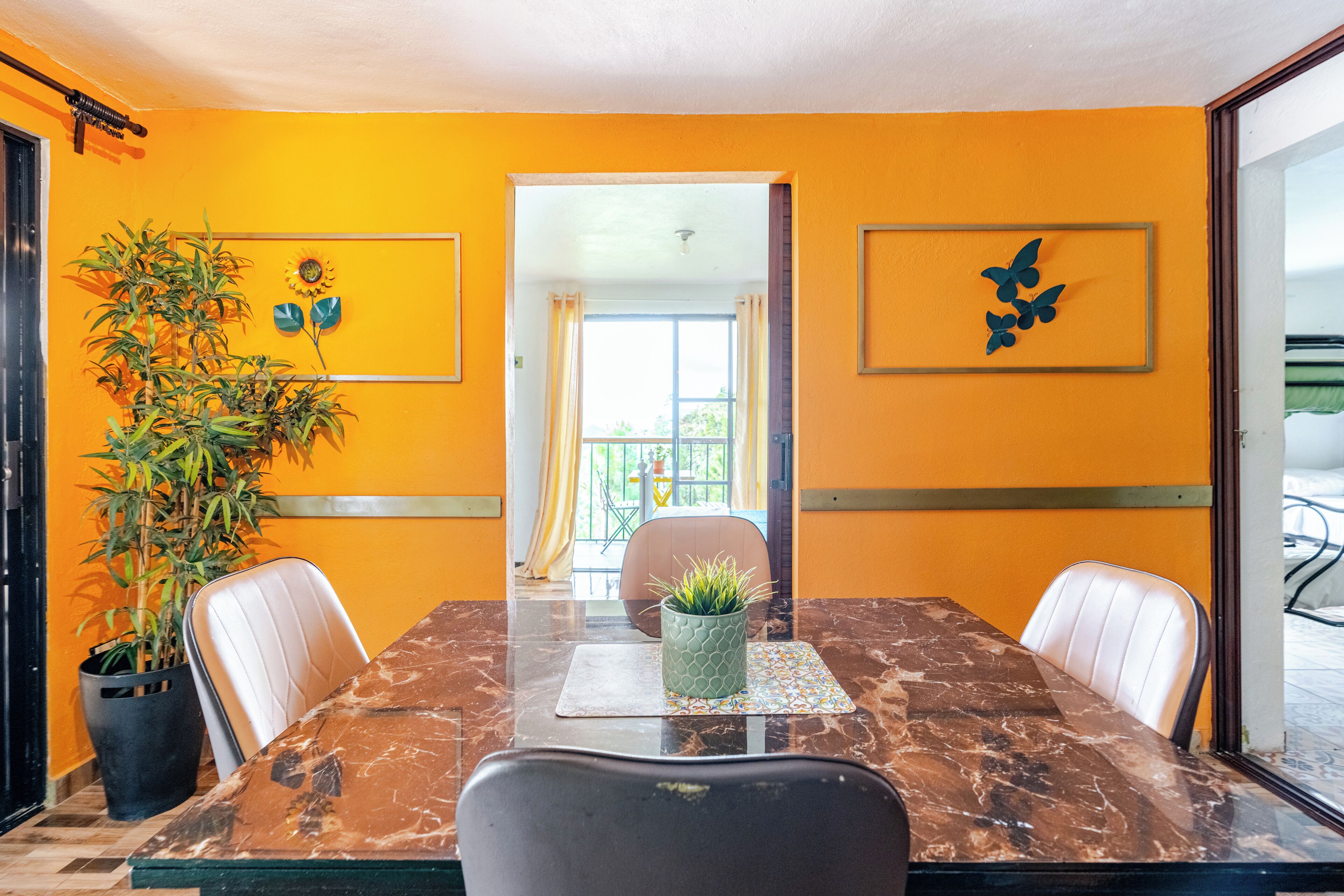 Un salón de conferencias con una mesa de mármol, dos sillas de cuero blanco, una planta en maceta y dos obras de arte enmarcadas en la pared.