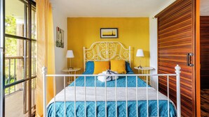 Un letto con struttura in metallo bianco, biancheria azzurra e bianca, e due lampade da comodino.