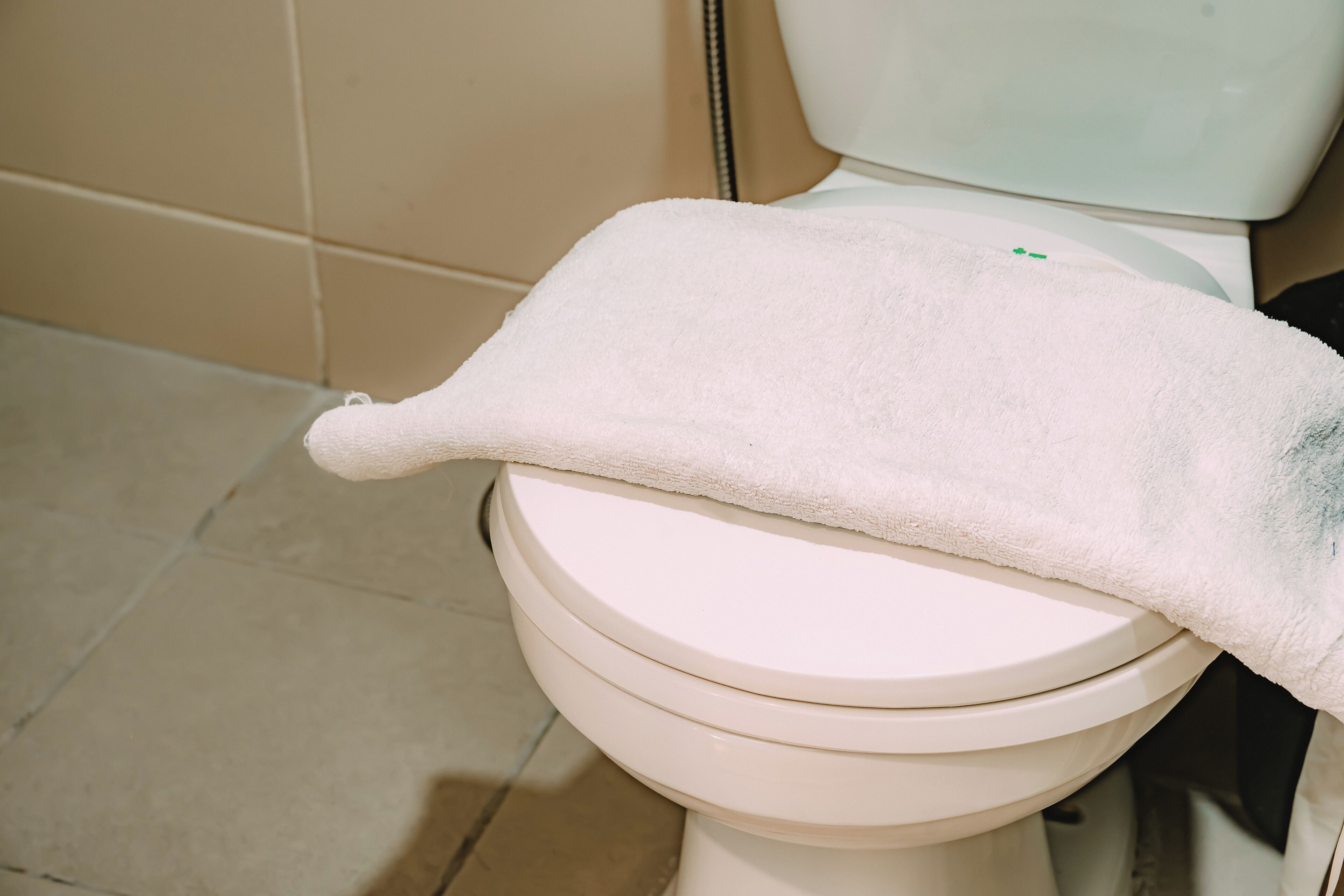 A white toilet with a white towel draped over the seat.