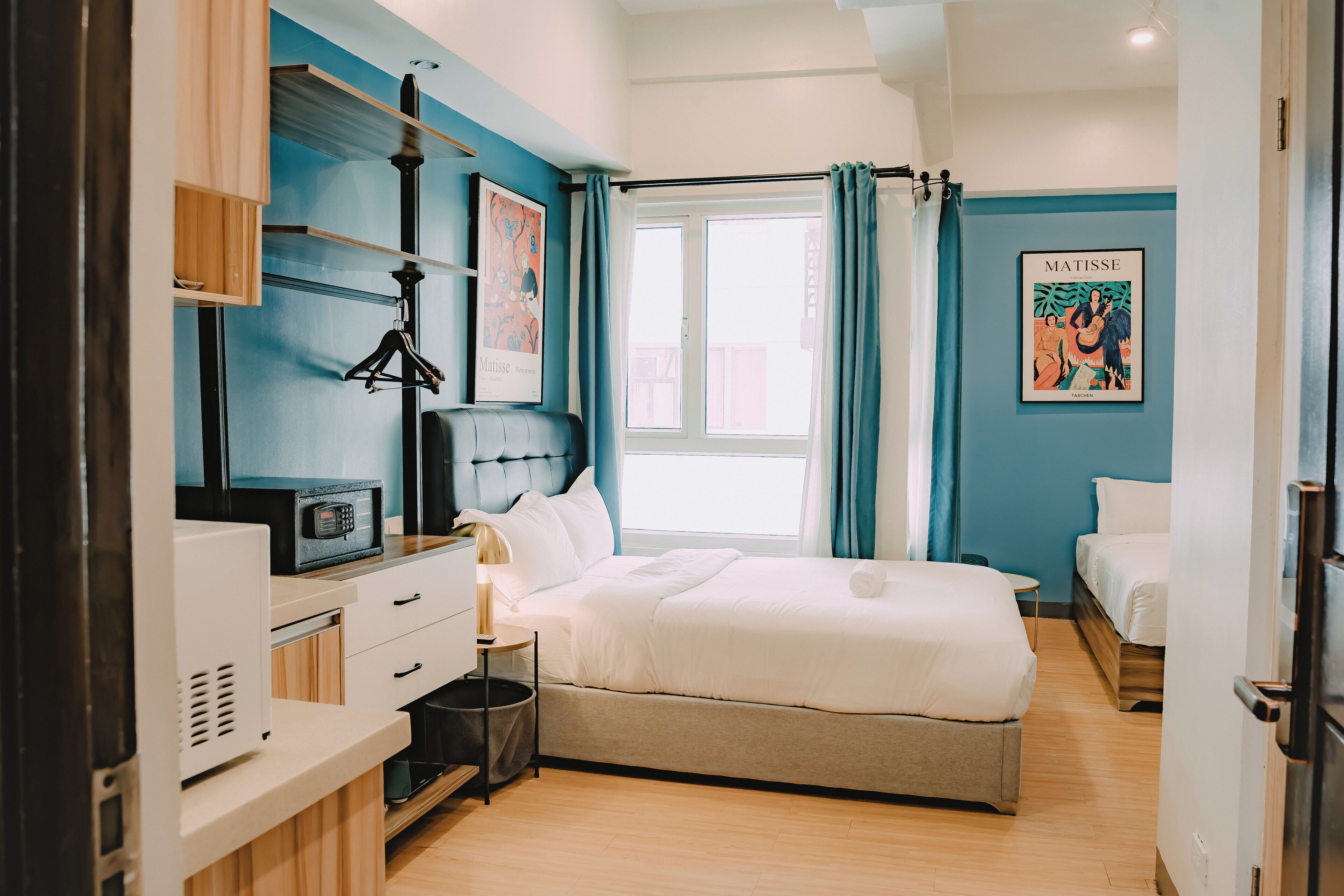 Een moderne hotelkamer met een bed, nachtkastje en een raam met gordijnen.