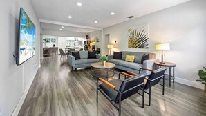 A modern living room with a grey sofa, a coffee table, and a TV mounted on the wall. - Your Hollywood Vacation Home (Hollywood)