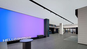A modern interior with a large illuminated wall displaying "HELLO.SHANGHAI", a reception area, and a seating area.