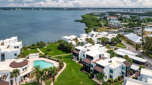 Un área residencial costera con casas modernas, una extensa masa de agua y un campo de golf al fondo.