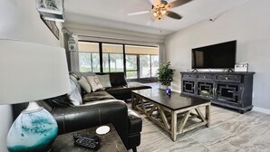Una sala de estar moderna con un sofá de cuero, una mesa de centro, un televisor y una chimenea.