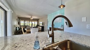 Una cocina con encimera de granito, pileta de acero inoxidable e iluminación colgante.