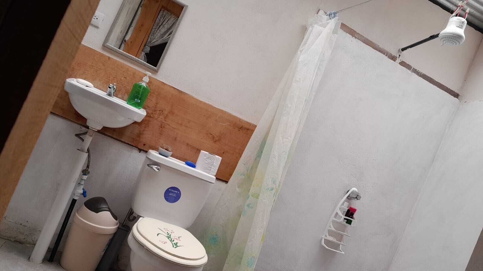 A small bathroom with a toilet, sink, and shower.