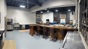 Un espace bar moderne doté d’une table de billard, de tabourets et d’un téléviseur à écran plat.