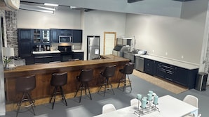 Une cuisine moderne avec des meubles de couleur sombre, un réfrigérateur en acier inoxydable et un coin bar avec des tabourets.