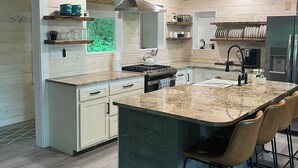 Una cocina moderna con una isla grande, techo de madera y electrodomésticos integrados.