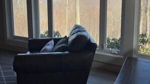 Una habitación con un ventanal grande, un sofá de cuero y techo de madera.
