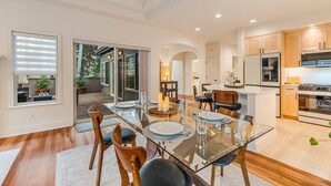 A modern kitchen with a glass dining table, wooden chairs, and a built-in oven. - Broken Top Villa One - A Beautiful Two Bedroom Villa in Bend's Westside! (Bend)