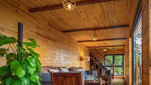 Un intérieur en bois comprenant un canapé, une table basse et un escalier menant à un balcon.