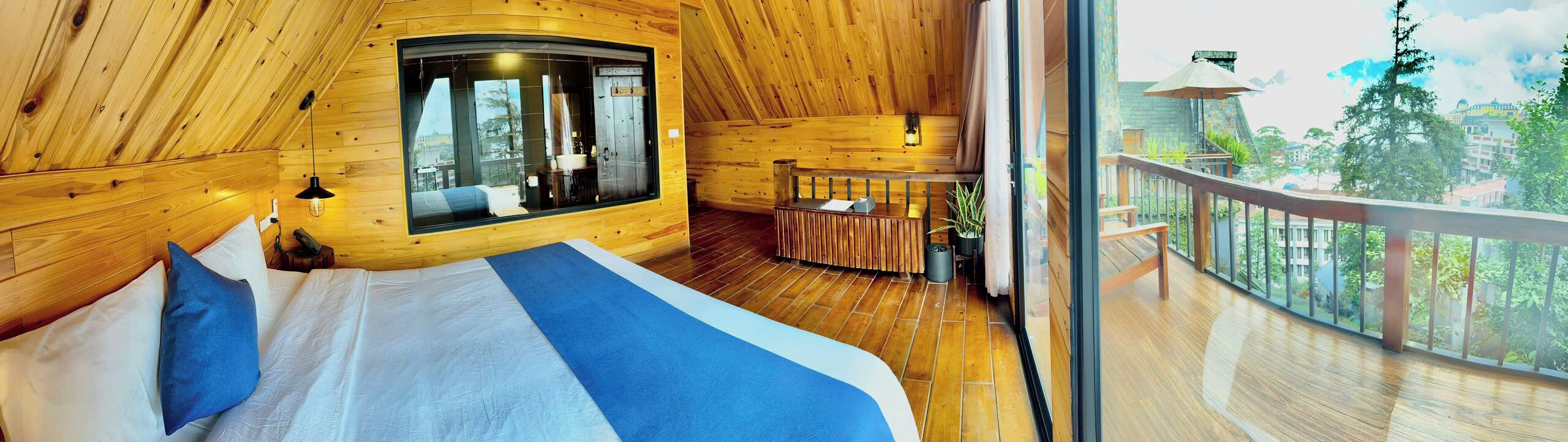Une cabane en bois avec un grand lit, une petite salle de bain et un balcon offrant une vue imprenable.