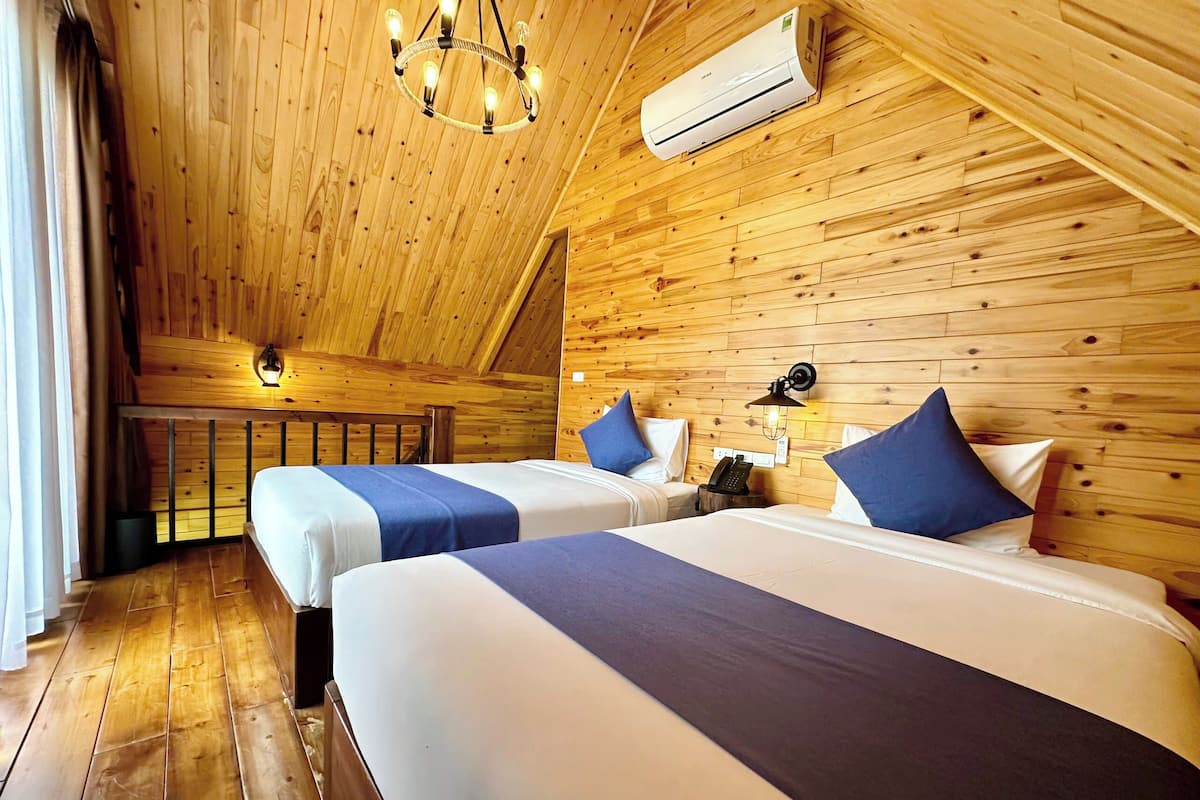 Ein Zimmer mit zwei Betten, Holzwänden, einer Klimaanlage, einem Kronleuchter und einem Telefon auf einem Nachttisch.