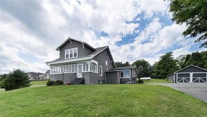 A two-story house with a large front porch, a garage, and a well-maintained lawn.