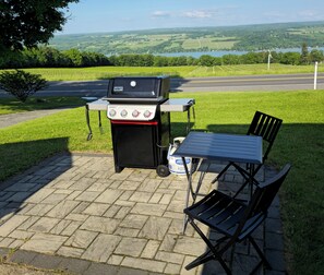 An outdoor patio with a grill, a table, and chairs. - 5BR Farmhouse Lakeview • Wine Trail • Cozy Porch (Dundee)