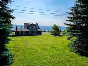 A house with a large grassy yard and a view of the water. - 5BR Farmhouse Lakeview • Wine Trail • Cozy Porch (Dundee)