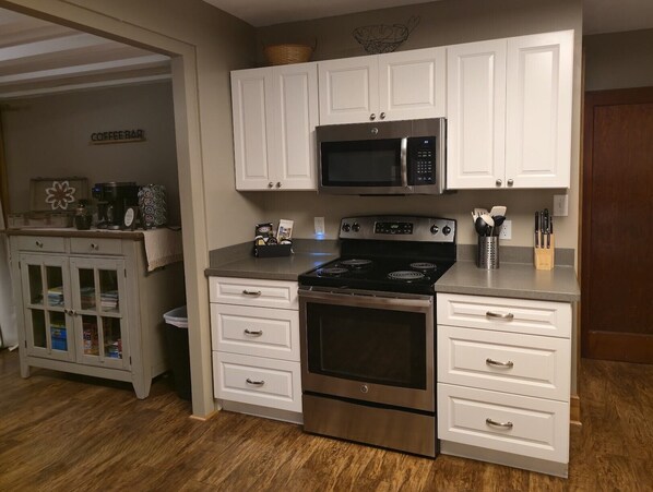 A kitchen with white cabinets, a stainless steel stove, a microwave, and a coffee bar. - 5BR Farmhouse Lakeview • Wine Trail • Cozy Porch (Dundee)