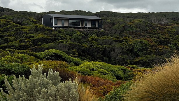 A modern house on a hillside with a view of the surrounding forest. - Welcome to Admiral Cabin, a luxurious off-grid retreat on King Island, Tasmania. (Nugara)