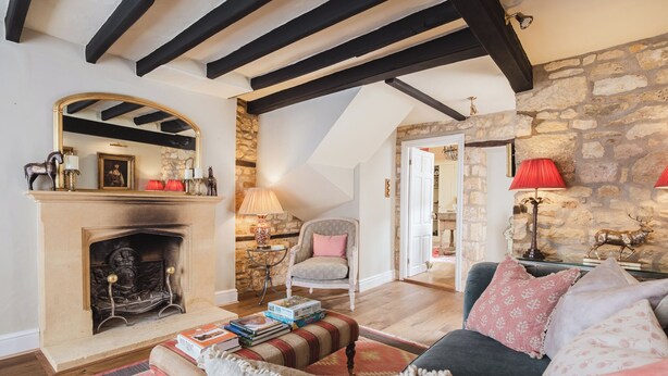 Una sala de estar acogedora con chimenea, pared de piedra y techo alto con vigas a la vista.