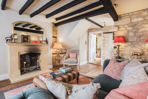 A cozy living room with a fireplace, a stone wall, and a high ceiling with exposed beams. - Hicks House-Lovely House in Leysbourne (Chipping Campden)