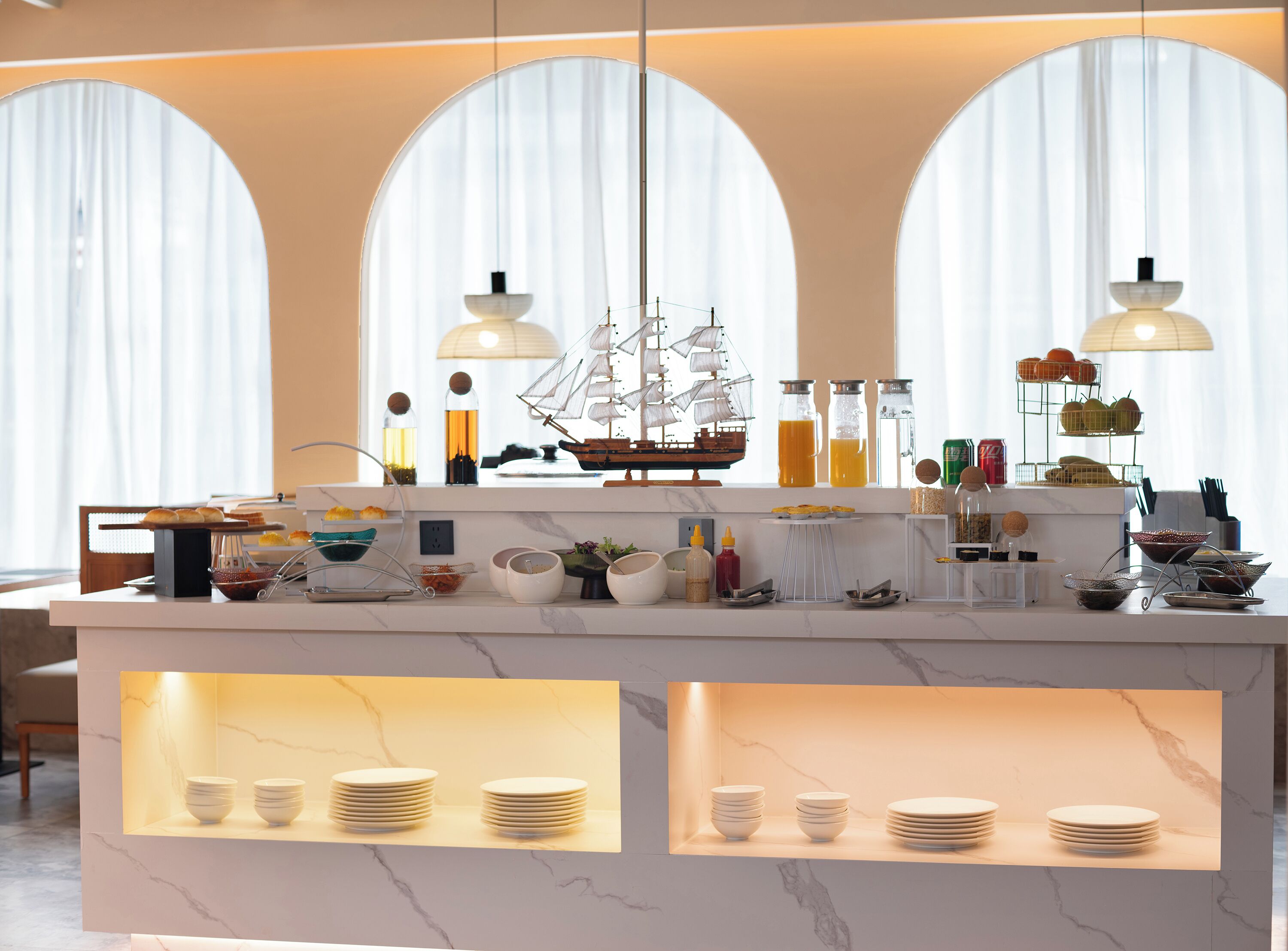 Una cocina moderna con encimera de mármol, un modelo de barco y varios utensilios de cocina.