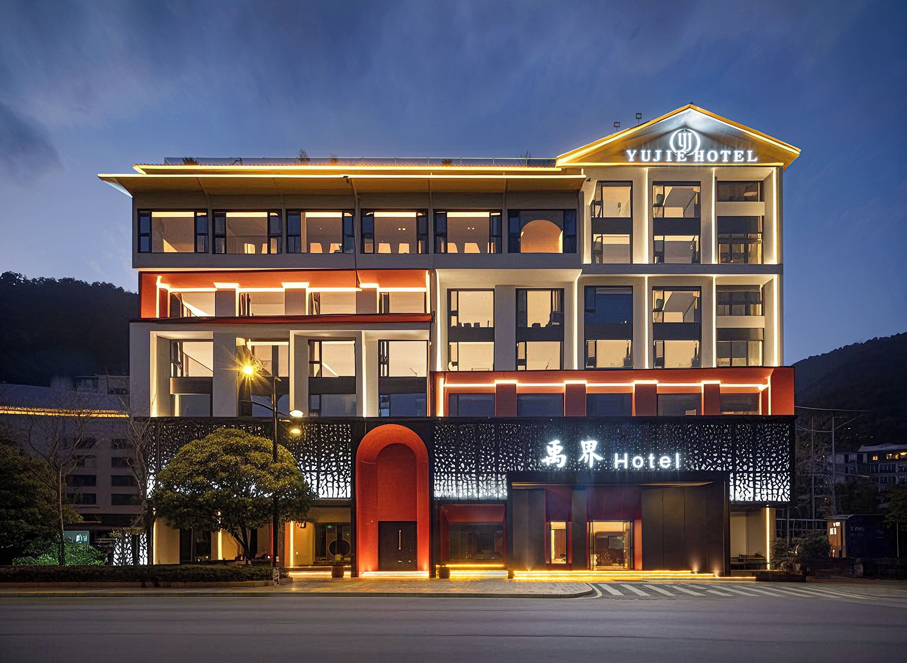 Un hôtel à plusieurs étages au design moderne, doté d’une entrée imposante avec une arche rouge et une enseigne lumineuse.