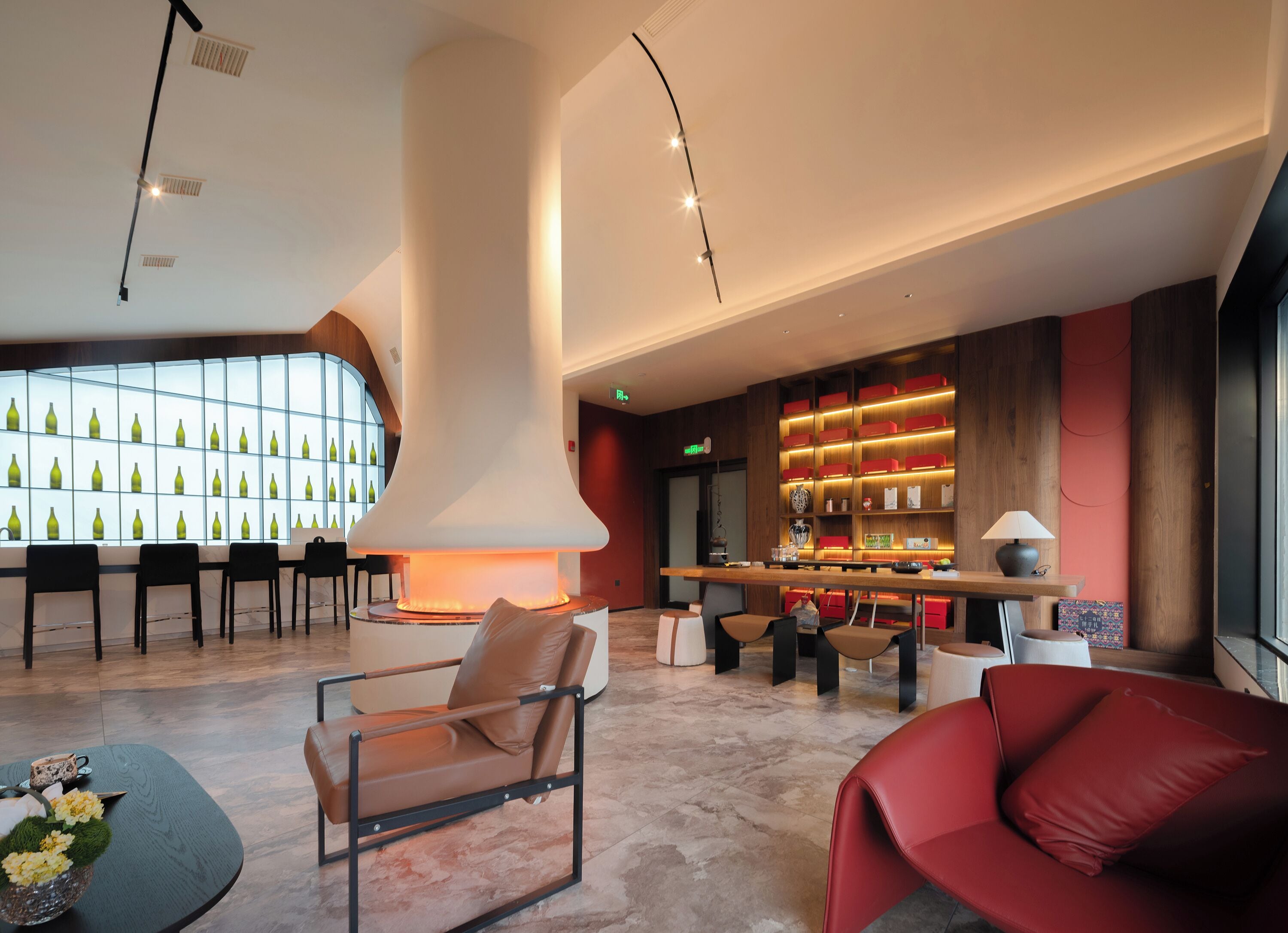 A modern lobby with a central column, seating area, and a bar with illuminated shelves.