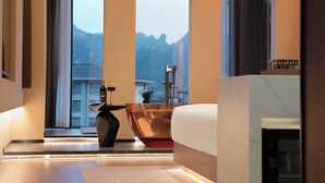 A modern bathroom with a bathtub, a large mirror, and a view of mountains through arched windows. - YUJIE HOTEL (Zhangjiajie)