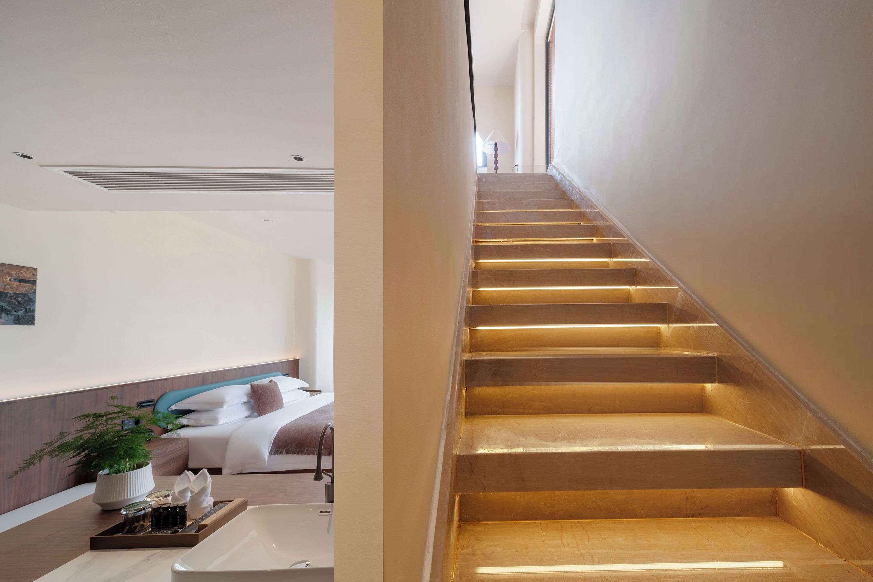 Une chambre d’hôtel moderne avec un escalier en bois, un lit avec une literie blanche, une table de chevet agrémentée d’une plante et un plateau avec des articles de toilette.