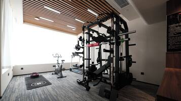 Ein Fitnessraum mit Klimmzugstange, Gewichtbank und Crosstrainer.