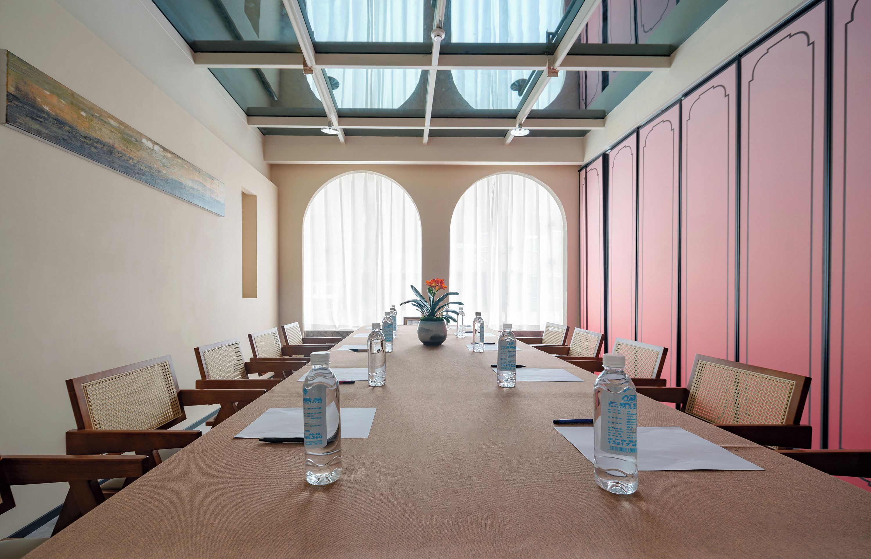 A conference room with a long table, chairs, water bottles, and a potted plant.