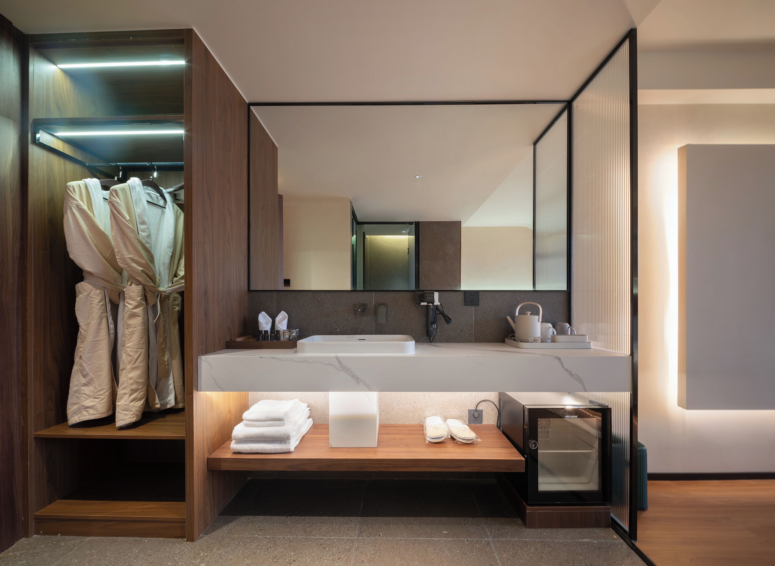 A modern bathroom with a large mirror, dual sinks, and a wooden vanity.