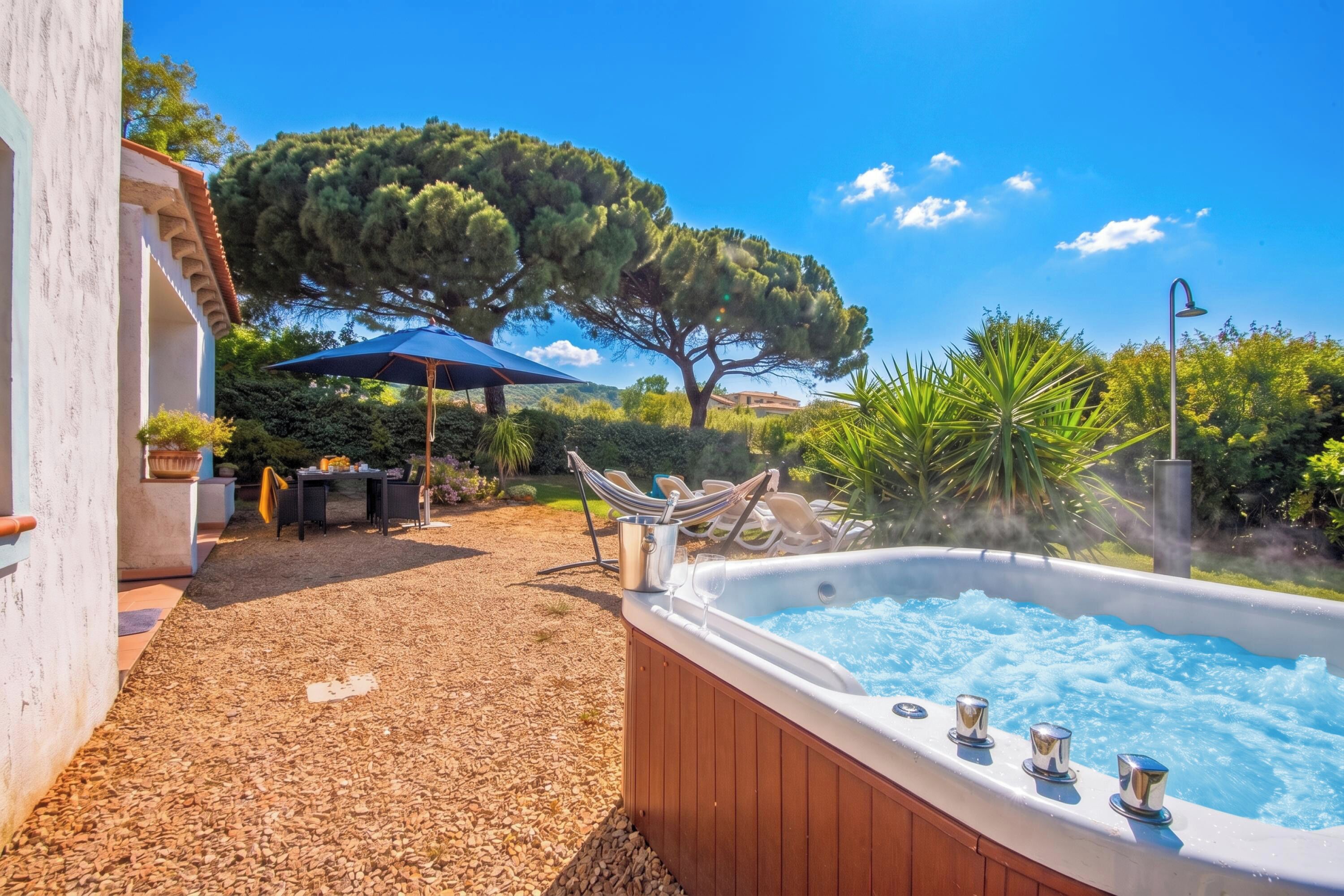Un bain à remous avec une terrasse en bois, une table avec des chaises et un hamac.