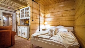 A wooden cabin bedroom with a bed, a wooden dresser, a lamp, and a sofa. - Salamandra 11 Apartamenty Góralskie (Koscielisko)