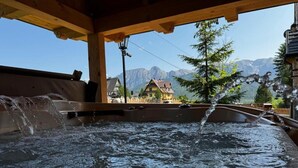A hot tub with water flowing, wooden beams overhead, and a mountain view in the background. - Salamandra 11 Apartamenty Góralskie (Koscielisko)