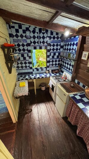 Een koelkast, een oven, een kookplaat, kookgerei, borden en bestek