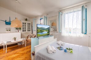 Een moderne slaapkamer met een bed, een bureau, een televisie en een raam met gordijnen.