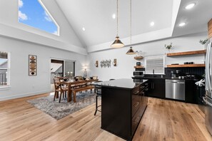A spacious kitchen with a central island, wooden flooring, and pendant lighting.