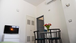 A small room with a bed, a TV on a dresser, a table with chairs, and a door leading to another room. - Apartment 'Viabalduini2' with Wi-Fi and Air Conditioning (Lecce)