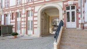 Un edificio con fachada roja y blanca, una entrada central en arco y una escalera que lleva a la entrada.
